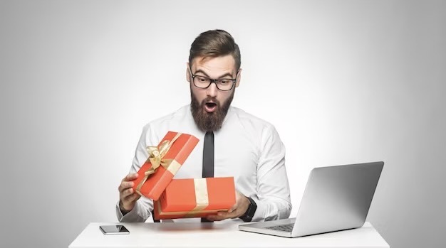Surprised young man in a white shirt opens a gift