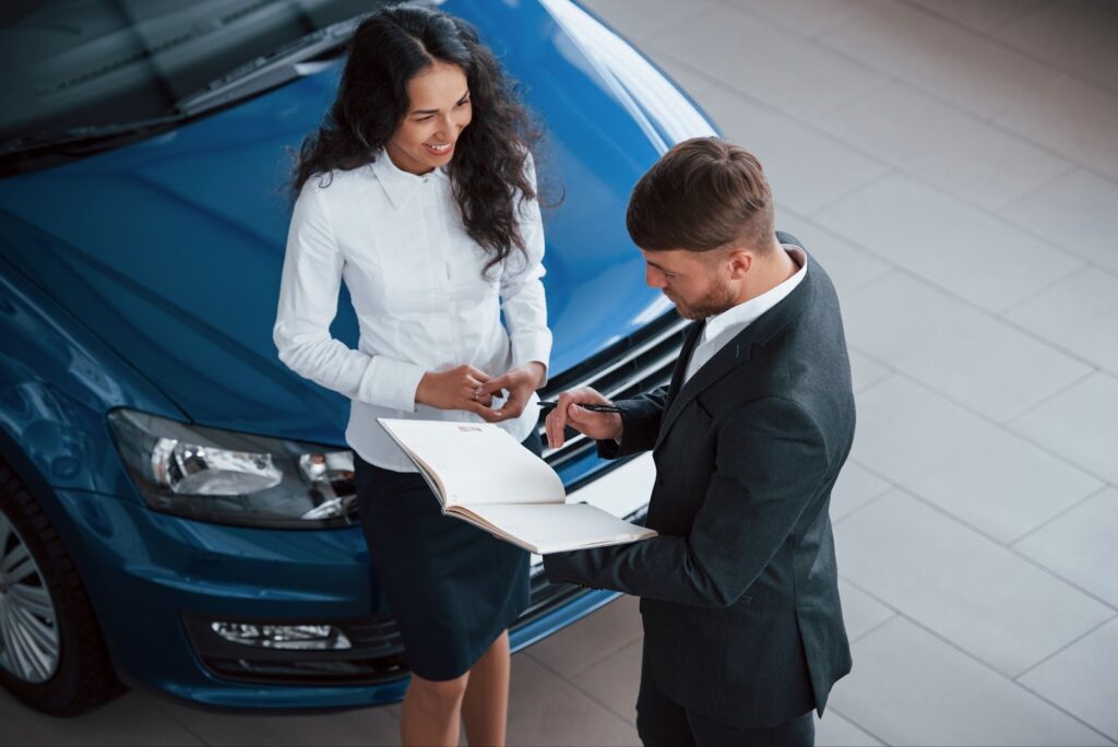 Man and woman speaking near blue car