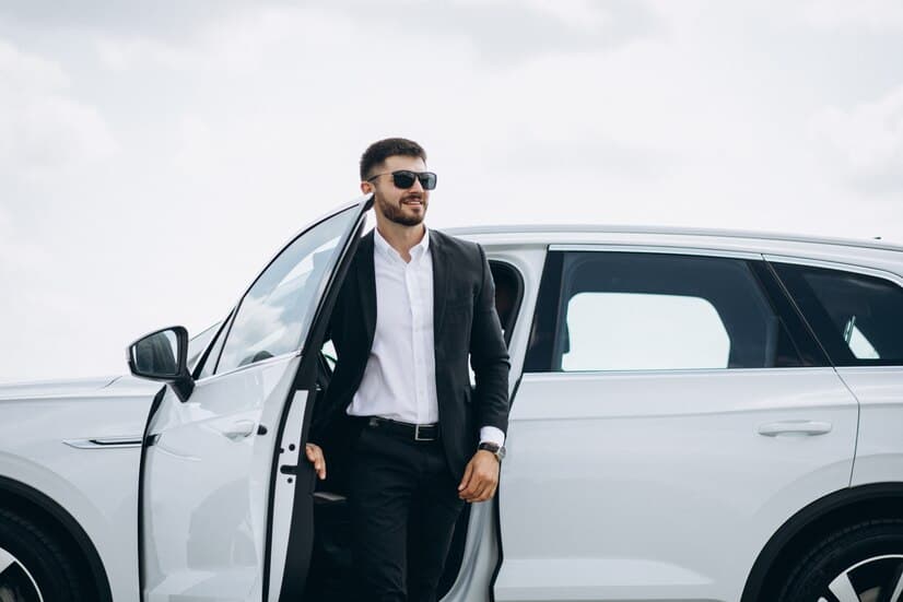 A Man in a Suit is Stepping Out of a White Car