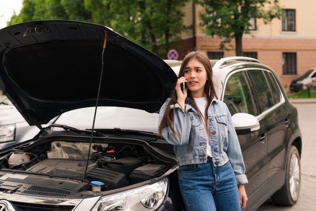 Woman sitting in front of her car and try to calling for assistance with her car broken down