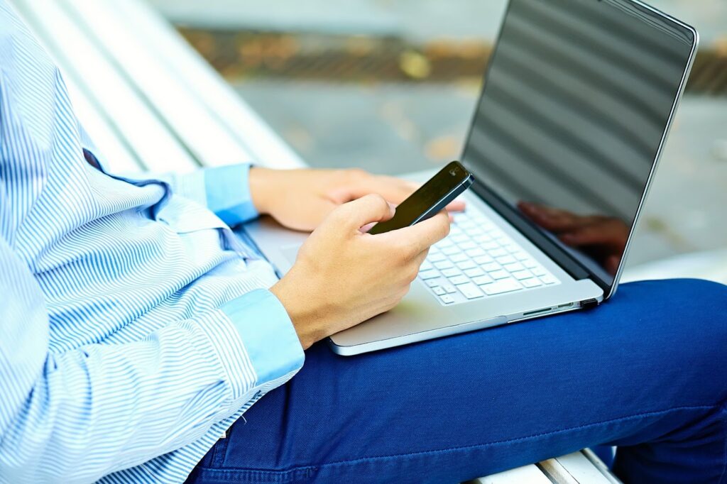 Man working with laptop and using his phone